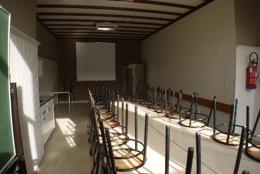 Een zicht naar de projector van de Cardijnzaal met de stoelen en tafels erbij