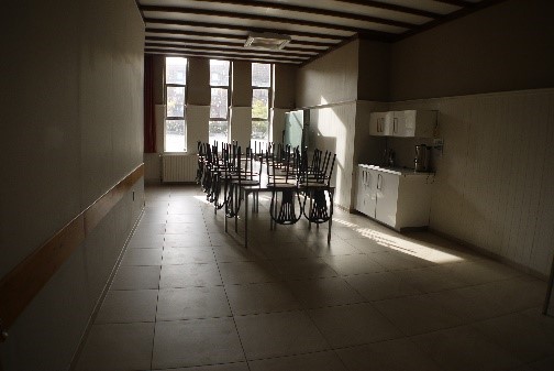 Een zicht richting de ramen van de Cardijnzaal met rechts een kleine keuken voor de afwas